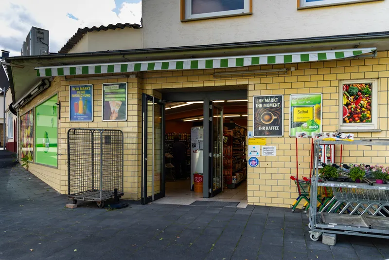 Eingangsbereich von Ihr Frischmarkt Selhof in Bad Honnef mit Einkaufswagen, Blumen und geöffneter Tür